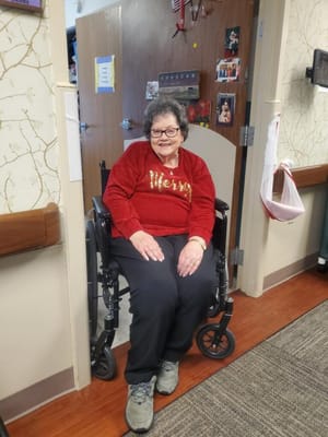 Resident smiling in a holiday-themed sweater in their room