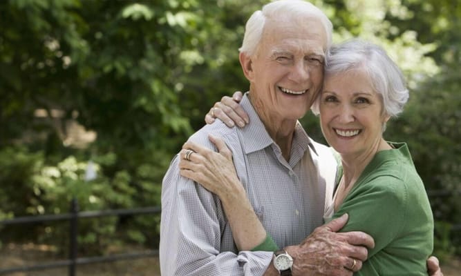 An elderly couple smiling together in a garden