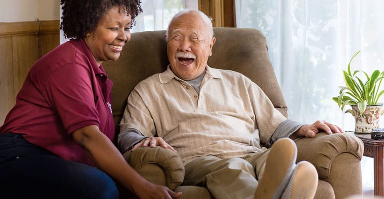 Staff member engaging with a smiling resident in a cozy setting