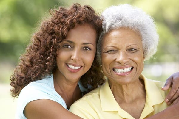 Two women smiling in a sunny outdoor setting