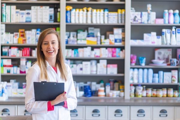 Pharmacist smiling in a well-stocked pharmacy