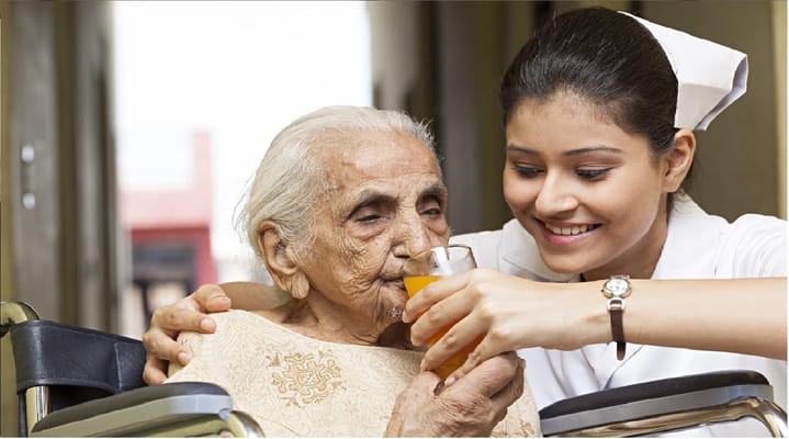 A caregiver assisting an elderly resident with a drink