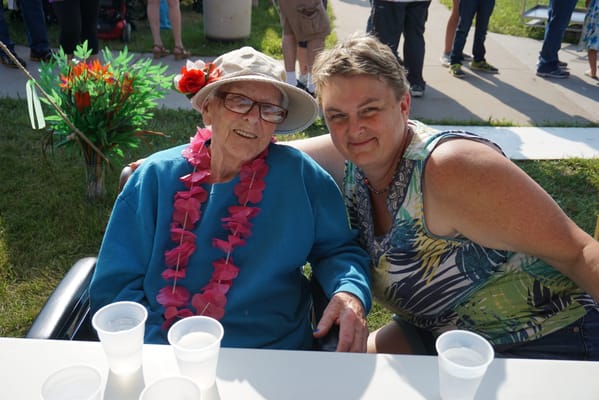Resident enjoying a festive outdoor event with a staff member
