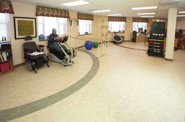 Resident exercising in a therapy room with equipment