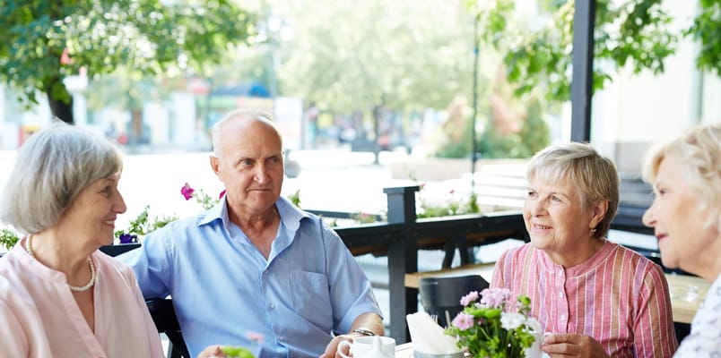Four residents enjoying coffee outdoors in a garden