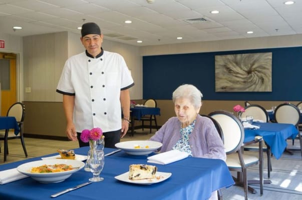 Chef serving a meal to a resident in the dining room