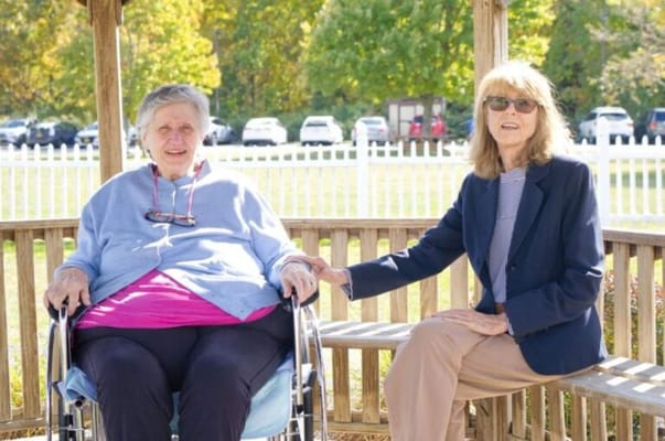 Two women sitting together in an outdoor gazebo