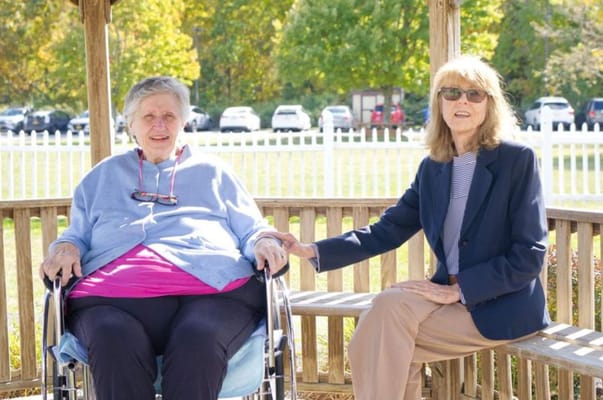 Two women sitting together in an outdoor gazebo