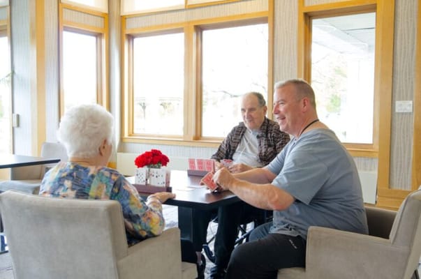 Residents and staff playing cards in a common area