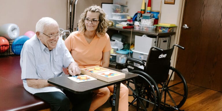 A resident and staff member engaged in a puzzle activity