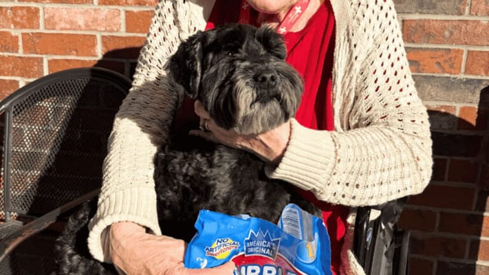 Senior resident holding a dog outdoors