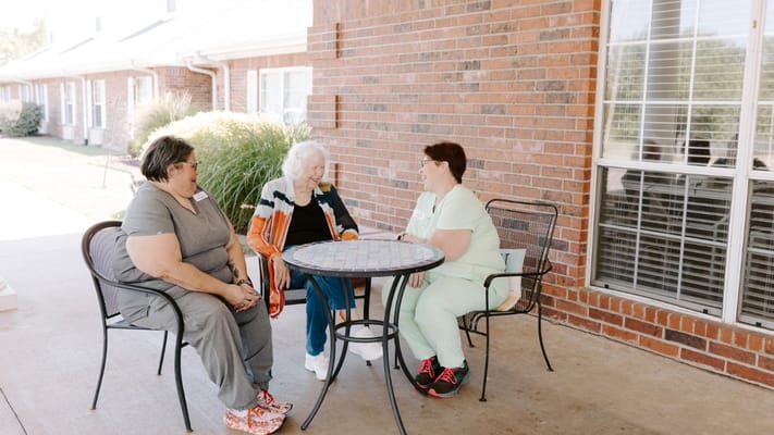 Three women chatting at an outdoor table