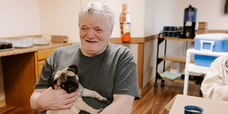 Resident holding a pug puppy in a communal area