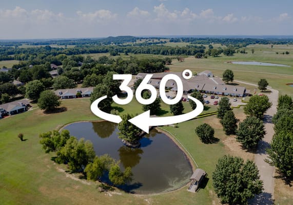 Aerial view of a senior living facility with a pond and greenery