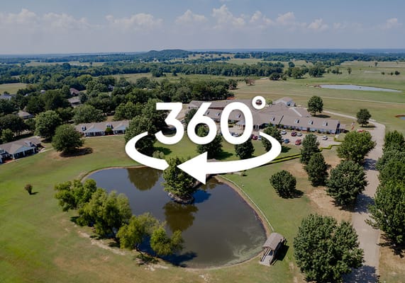 Aerial view of a senior living facility with a pond and greenery