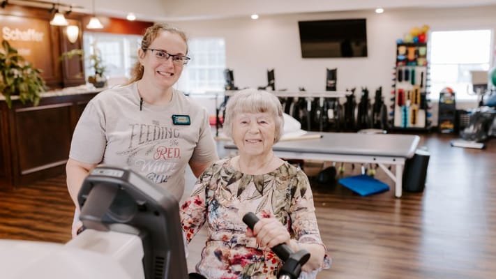 A staff member assisting a resident in a fitness area
