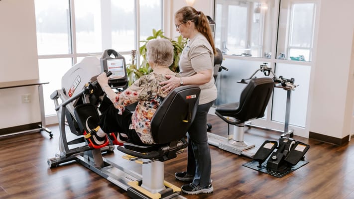 Resident using rehabilitation equipment with staff assistance