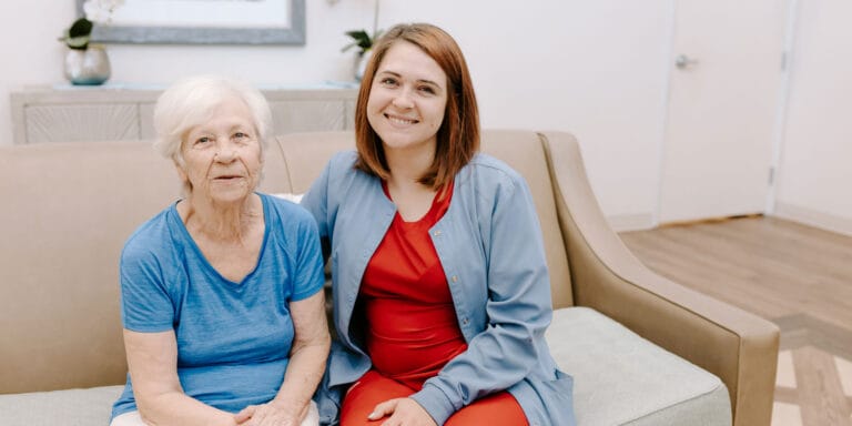 A resident and staff member smiling together in a common area