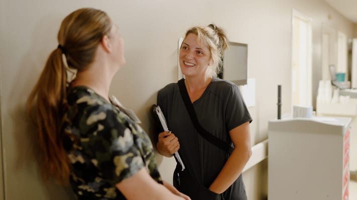 Two staff members chatting in a hallway