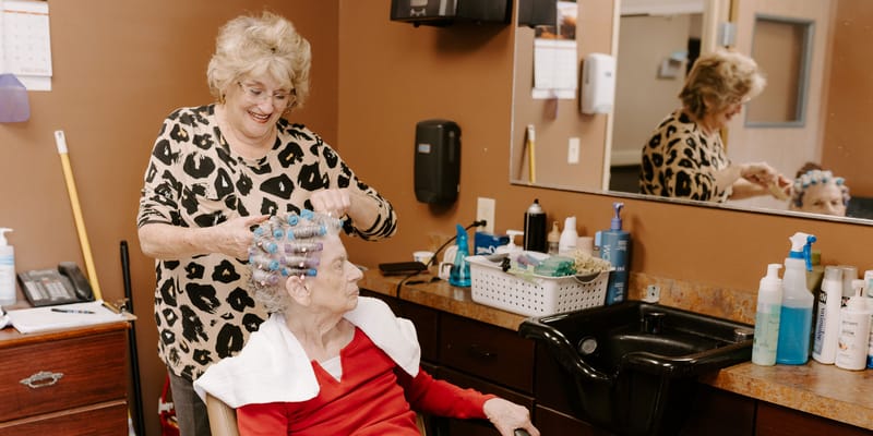 Stylist giving a hair treatment to a resident