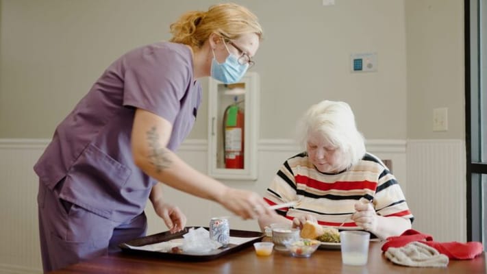 Staff serving food to a resident in a dining area