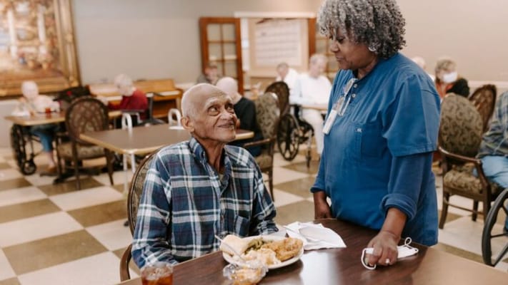 Resident enjoying a meal with a staff member