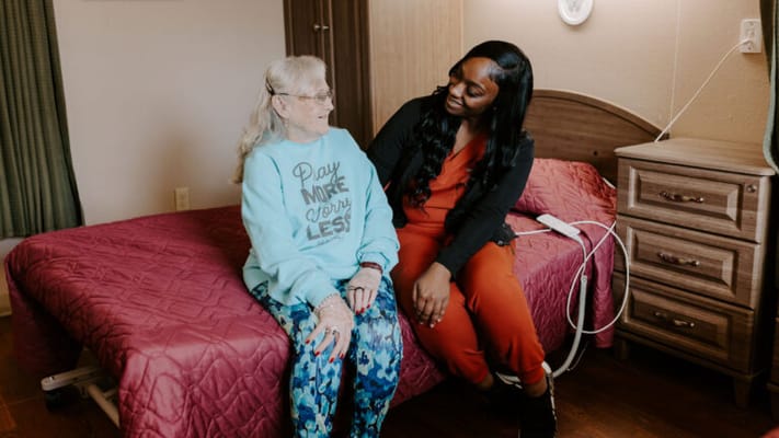 A caregiver interacting with a resident in her room