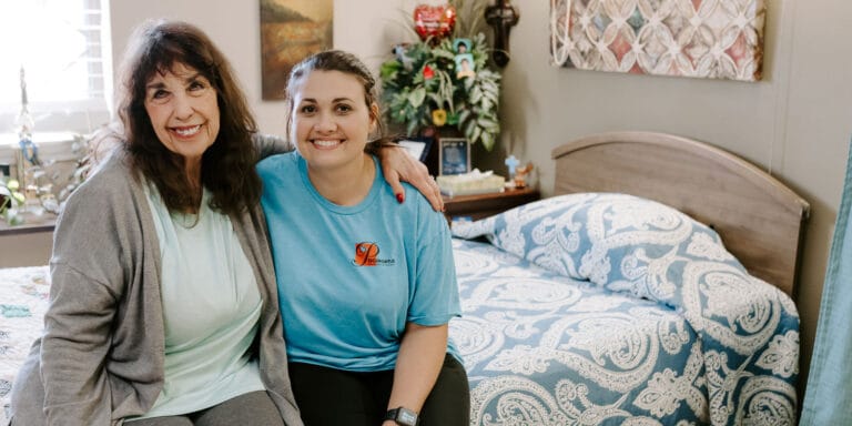 Resident and staff member smiling together in a room