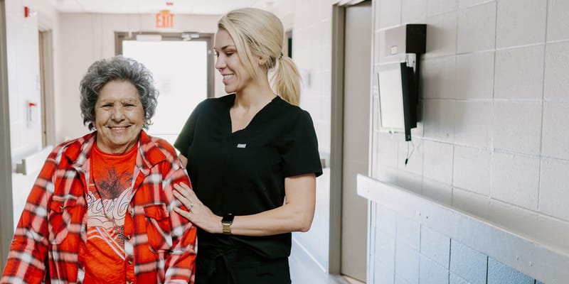 A resident and staff member walking in a hallway