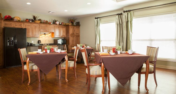 Bright dining area with set tables and kitchen in background