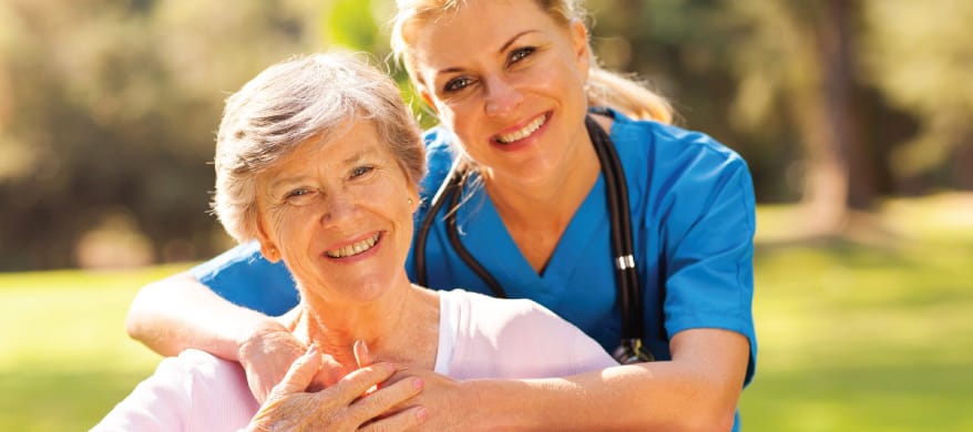 Nurse and resident smiling in a garden
