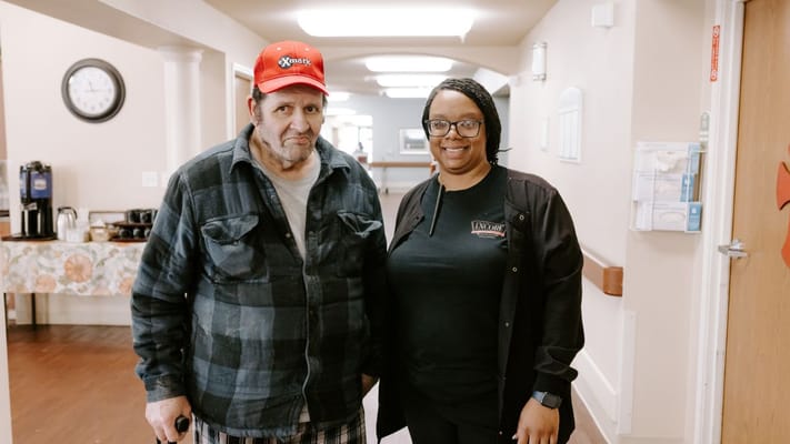 A resident and staff member smiling in the hallway
