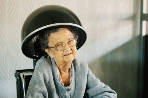 Resident using a hair dryer in a salon chair
