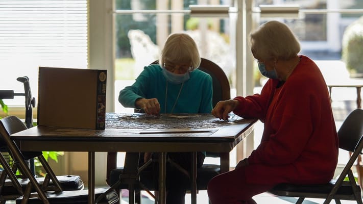 Two residents working on a jigsaw puzzle indoors
