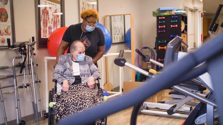 A caregiver assisting a resident in a rehabilitation area