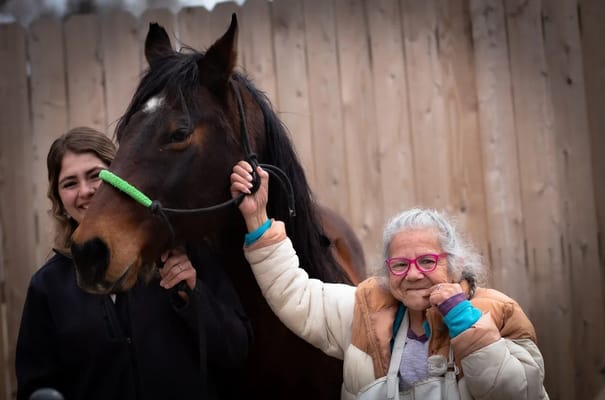 An elderly woman with a horse and a staff member
