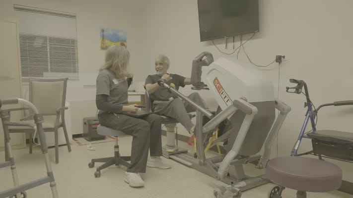 Resident using therapy equipment with staff assistance