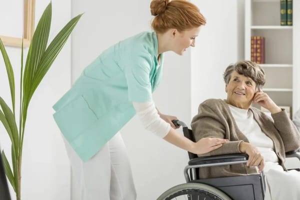 Caregiver assisting a smiling resident in a wheelchair