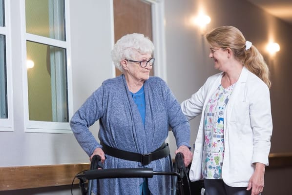 Caregiver assisting senior resident in a hallway