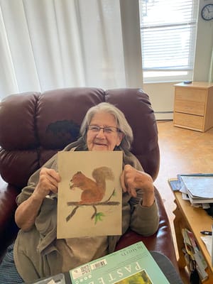Resident showcasing their artwork in a cozy chair