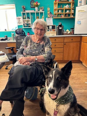Resident smiling with a dog in a cozy interior