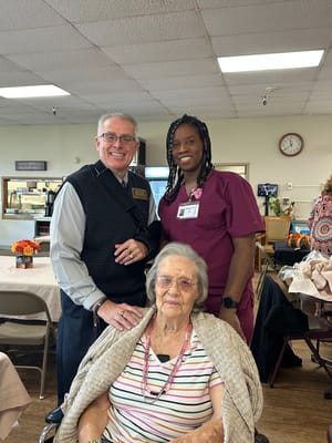 A caregiver and staff member with a resident in a common area