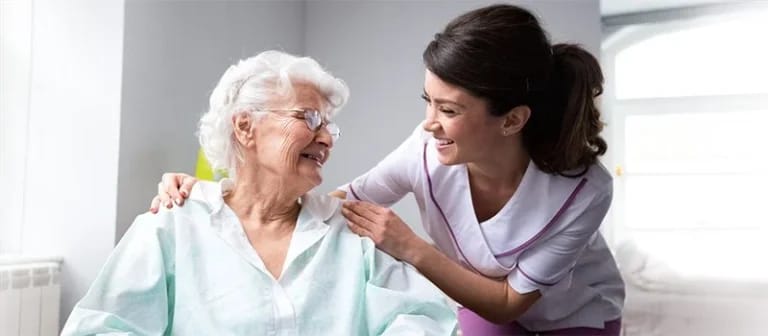 Staff assisting a smiling senior resident