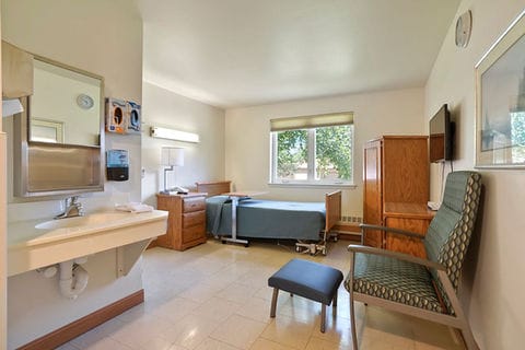 A private resident room with a bed and chair