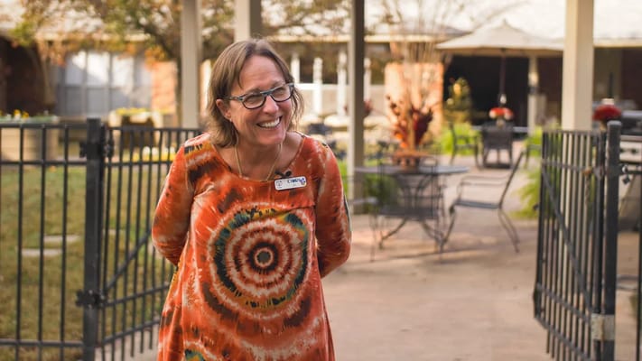 Staff member smiling outdoors in a garden area