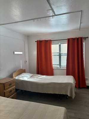 A bright private resident room with beds and curtains