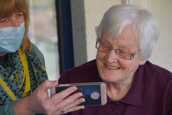 Staff member showing photos to a smiling resident