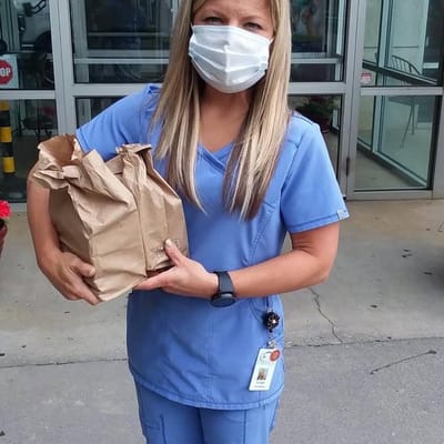 Staff member holding a food delivery outside the facility