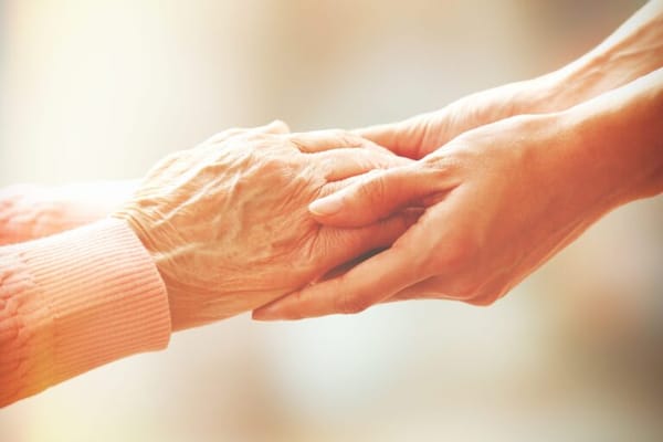 Tender moment between a caregiver and resident hands