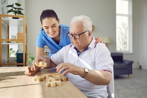 A caregiver assisting a senior with a puzzle at a table